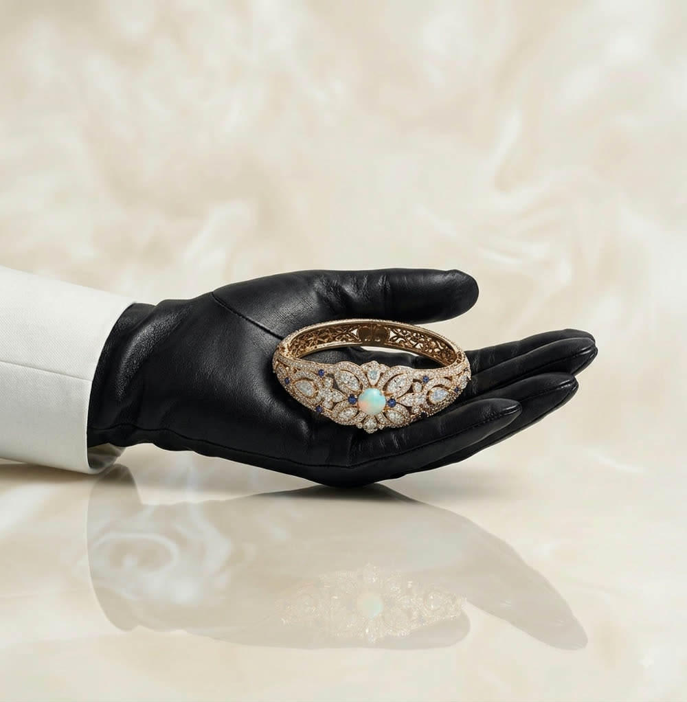 A gloved hand presenting a bespoke diamond and opal bangle