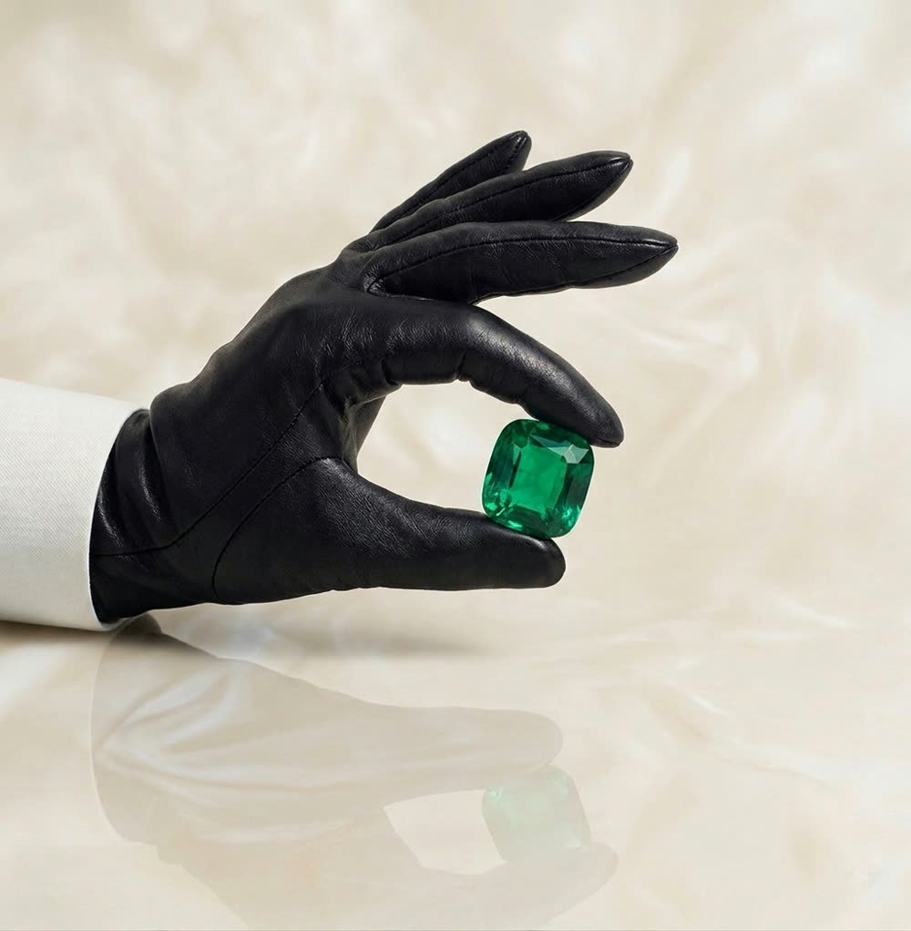 A gloved hand holding a large emerald-cut emerald